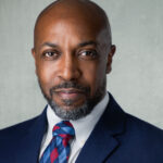 Professional male headshot in a suit with a patterned tie, suitable for business branding and corporate photography.